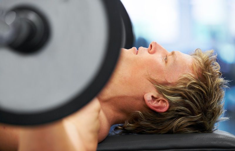 Closeup profile of a man exercising on the bench press
